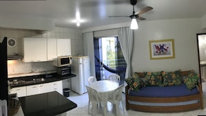A compact living space with a kitchenette, a dining area, and a sofa with patterned cushions. - KASATO MARU RESIDENCE (Florianópolis)