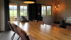 Comedor con mesa y sillas de madera, ventanas amplias y lámparas colgantes.