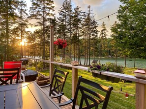 An outdoor seating area with a view of a lake and forest. - Eagles Run on Seavey Cove: Relaxation and Sea Breezes (Tenants Harbor)