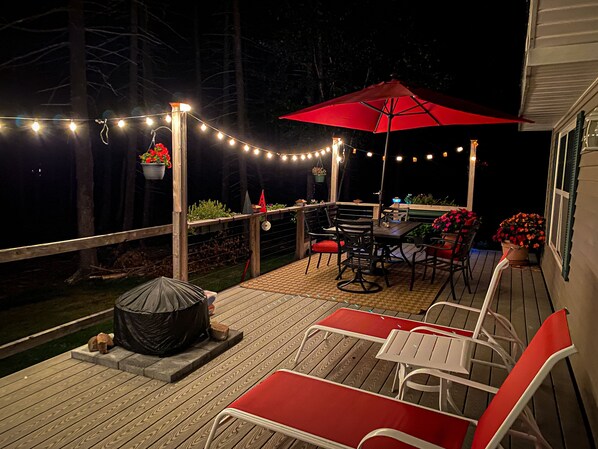 A deck with outdoor furniture, string lights, and potted plants. - Eagles Run on Seavey Cove: Relaxation and Sea Breezes (Tenants Harbor)