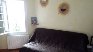 A room with a covered sofa, a radiator, a window with blinds, and two wall-mounted mirrors. - For nature lovers (SAINT MARTIN DE PALLIERES)