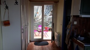 A kitchen with a sink, a radiator, and a door leading to an outdoor area with a table and chairs. - For nature lovers (SAINT MARTIN DE PALLIERES)