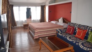 Una habitación de hotel con cama, sofá, mesa de centro y televisión.