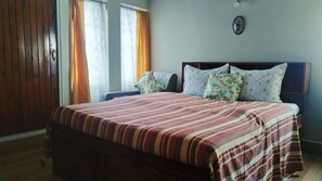 Un dormitorio con cama, dos mesitas de noche, cabecero de madera y un espejo montado en la pared.