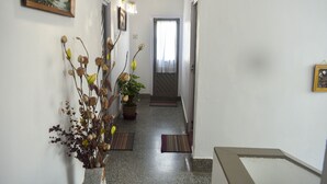 Un pasillo con una planta en maceta, un cuadro enmarcado y una puerta al final.