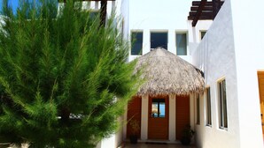 A white building with a wooden door and a thatched roof. - Iz Cay Luxury Ocean Front Villa (Progreso)
