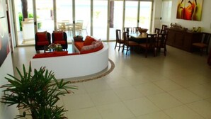 A spacious living area with a curved white sofa, red cushions, and a dining table with chairs. - Iz Cay Luxury Ocean Front Villa (Progreso)