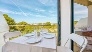 A table set for two on a balcony with a clear view of greenery and a blue sky. - BEAUTIFUL DUPLEX IN CALA SANTANDRIA-CIUTADELLA WITH POOL AND WIFI (Cala Santandria-Ciutadella-Islas Baleare)