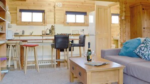 A wooden cabin interior with a kitchen, dining area, and living room.