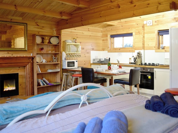 Un acogedor interior de cabaña con cama, chimenea, comedor y cocina.
