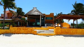 A resort with a thatched-roof structure, a covered seating area, and a sandy beach. - Uinic Chay Luxury Ocean Front Villa (Progreso)