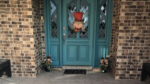 A teal double door with diamond-patterned glass panels, a metal doorbell, and a small step leading to the entrance. - El Castillo (The Castle) (McAllen)