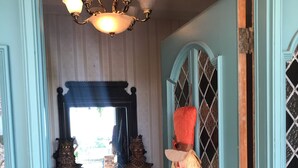 A hallway with a dark wooden cabinet, a mirror, and a decorative door with a welcome mat. - El Castillo (The Castle) (McAllen)