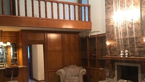 A spacious living room with a high ceiling, a wooden staircase, a fireplace, and a large mirror. - El Castillo (The Castle) (McAllen)