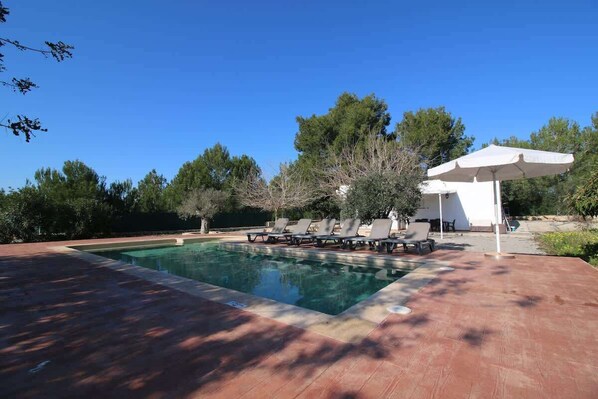 A swimming pool with lounge chairs and a pergola.