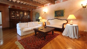 Una sala de estar con techo de madera, un sofá blanco, una mesa de centro y dos lámparas sobre mesitas de noche.