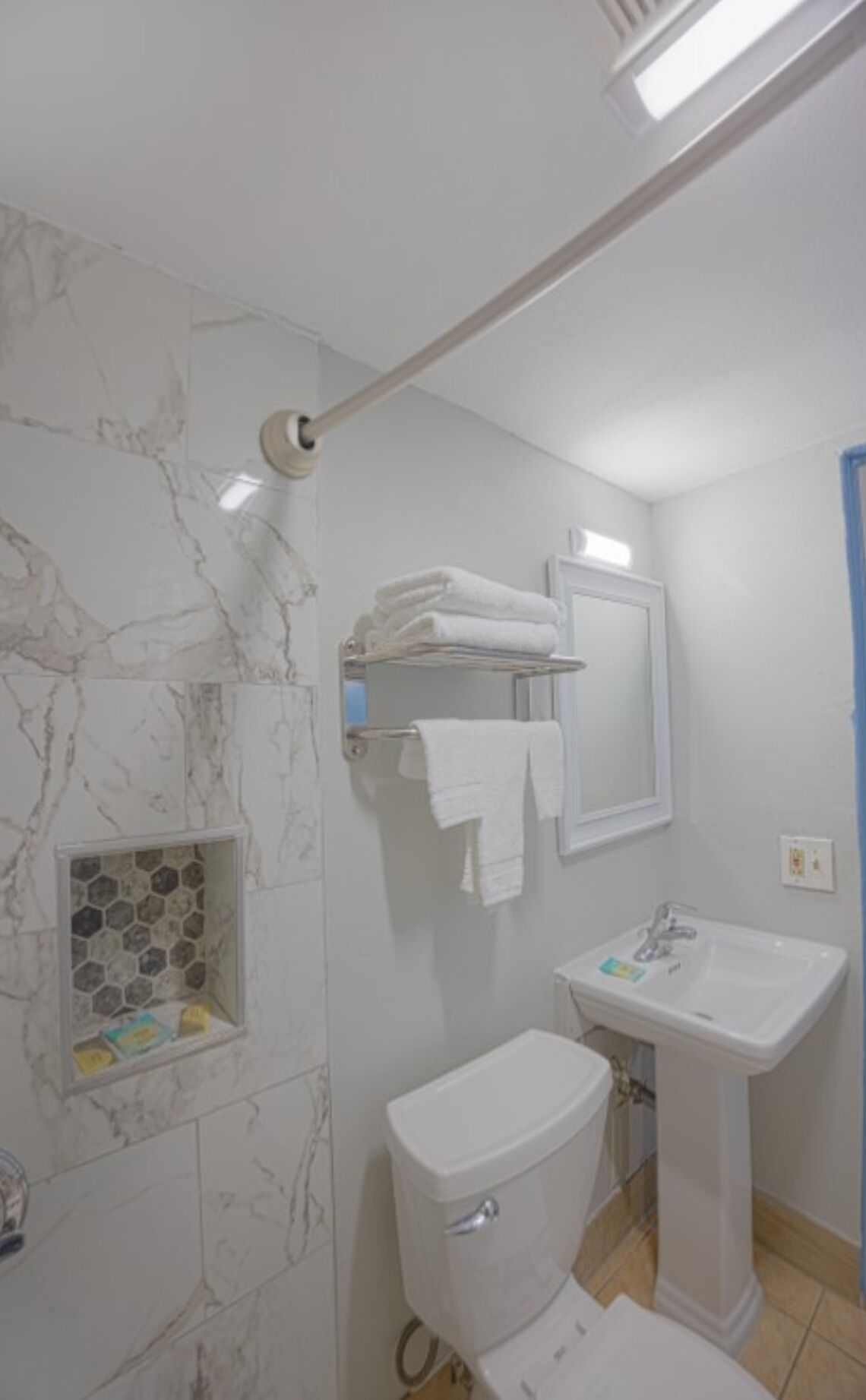 A bathroom with a toilet, sink, and towel rack.