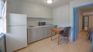 A kitchen with a refrigerator, microwave, and a dining table with a chair. - Aladdin Motel By OYO Merritt Island (Merritt Island)