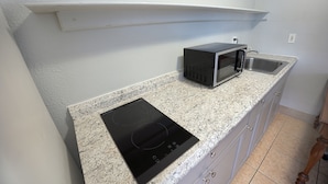 A kitchen with a built-in microwave, an induction cooktop, and a sink. - Aladdin Motel By OYO Merritt Island (Merritt Island)