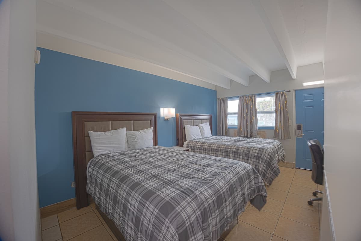 A hotel room with two beds, a desk, and a chair.