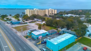A coastal view of a hotel with a parking lot, a road, and a body of water in the background. - Aladdin Motel By OYO Merritt Island (Merritt Island)