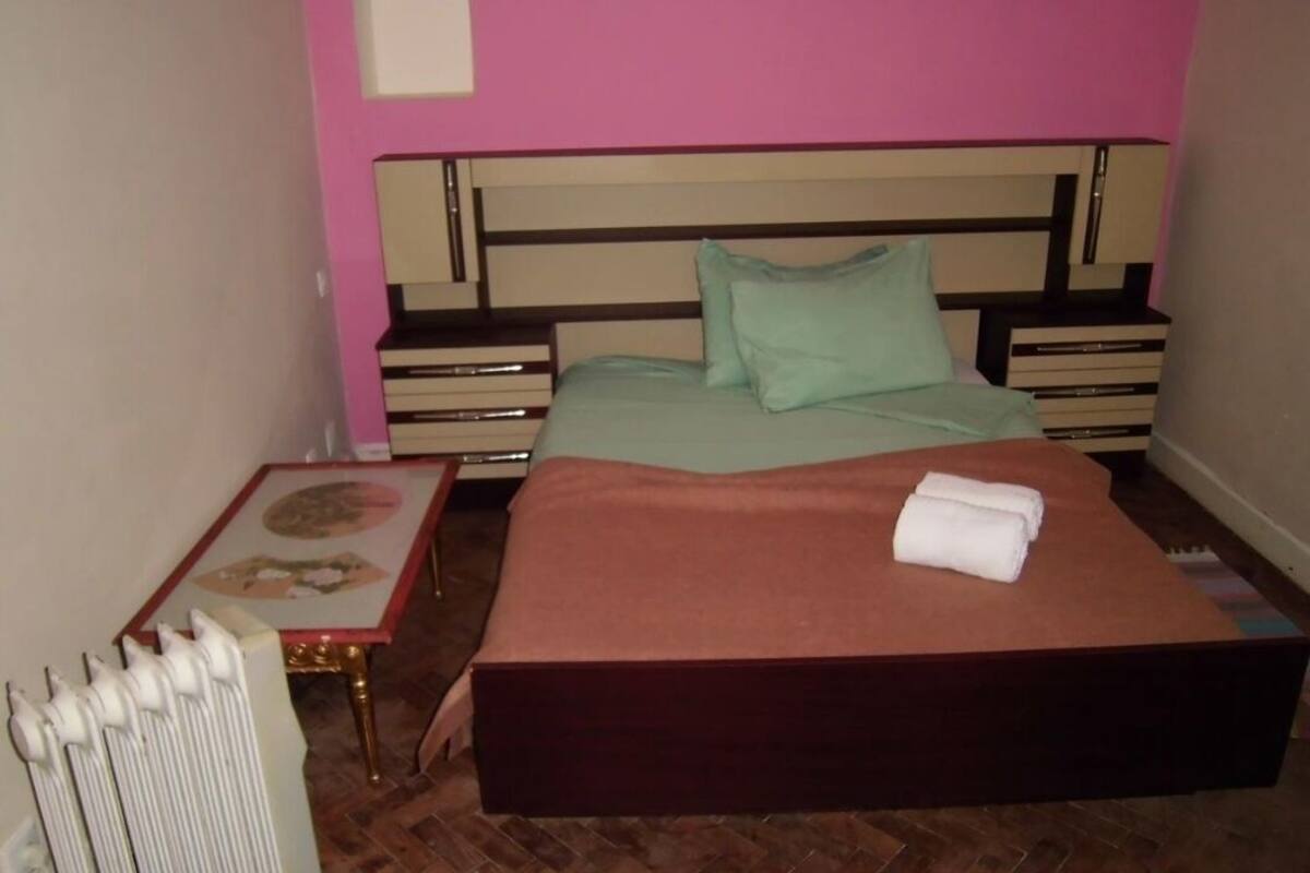 A bedroom with a bed, bedside tables, and a radiator.