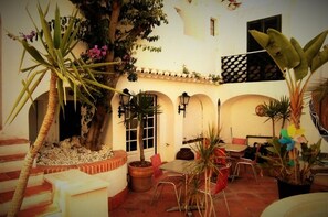 A courtyard with a dining area, potted plants, and a staircase leading to an upper level.