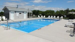 A swimming pool with lounge chairs and a small building, likely a changing room or storage, surrounded by trees. - Cottage #13 - 3 bedroom/ 1 bath (Cape Vincent)