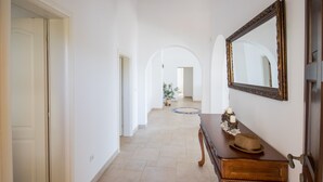 A hallway with a wooden dresser, a mirror, and a potted plant.