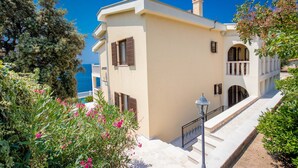 A Mediterranean-style building with a balcony, a staircase, and a view of the sea.