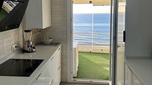 A modern kitchen with a view of the ocean through an open door. - BEACHFRONT APARTMENT IN FUENGIROLA (Fuengirola)