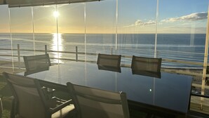 A table with chairs facing a large window overlooking the ocean. - BEACHFRONT APARTMENT IN FUENGIROLA (Fuengirola)