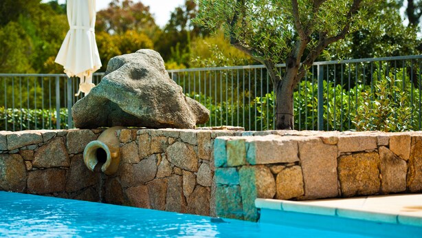A pool with a stone wall and a rock feature.