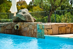 A pool with a stone wall and a rock feature. - Apartments in Residence with swimming pool (Sainte-Lucie de Porto-Vecchio)
