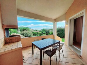 Enjoy a tranquil view of the lush garden and distant hills from this balcony, complete with a grill and comfortable seating for four.