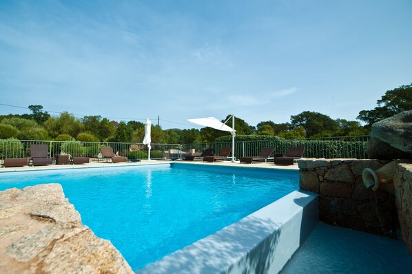 Relax by the serene pool surrounded by lush greenery and trees.