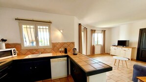 A compact kitchen with a microwave, sink, and dishwasher. There is a small dining area with a table and a chair.