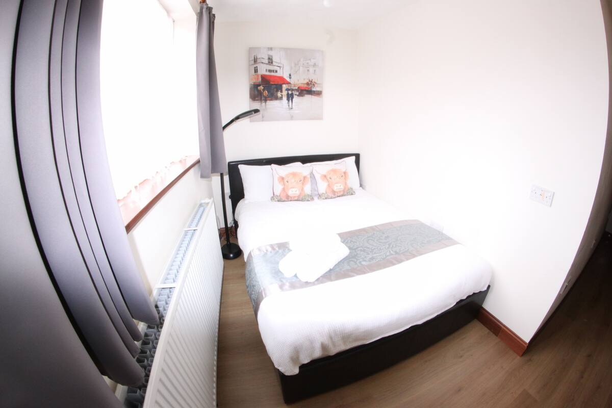 Ein Hotelzimmer mit Bett, einem fensterbelaubten Fenster, einem Wandbild und einer Heizung.