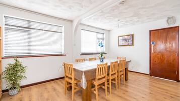A dining area with a wooden table and chairs, a potted plant, and a wooden door.