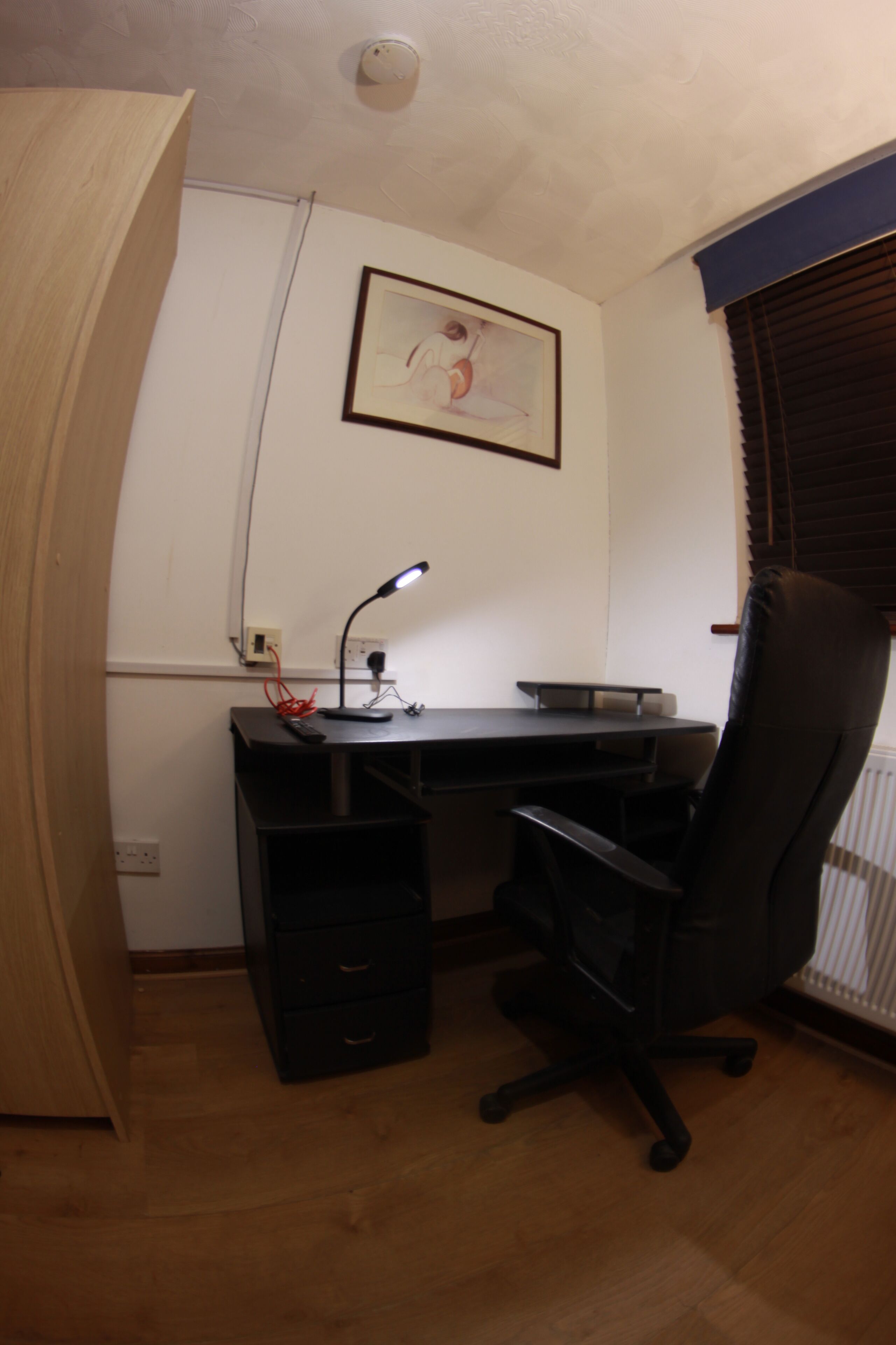A small office space with a desk, chair, and a framed picture on the wall.