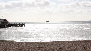 A pier extending into calm waters with a rocky shoreline. - College Street Abode - Guest House (Portsmouth)