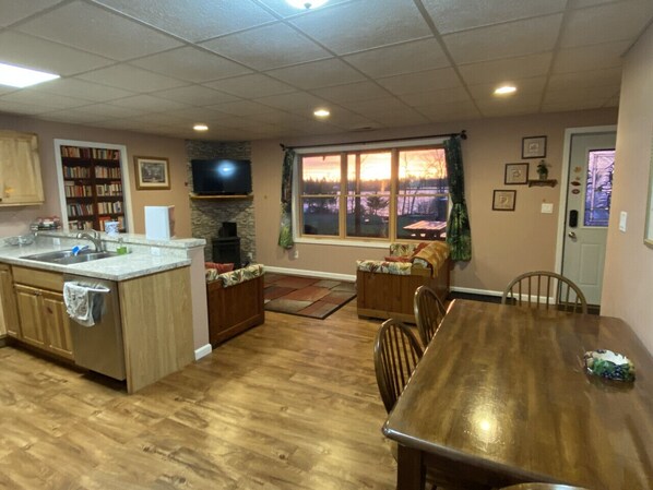 A spacious kitchen with wooden cabinets, a dining table, and a large window offering a view of the outdoors.