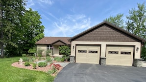 A two-story house with a garage, a driveway, and a landscaped garden. - Hidden Charm Suites - Peaceful Suite Lake Retreat (Lapeer)
