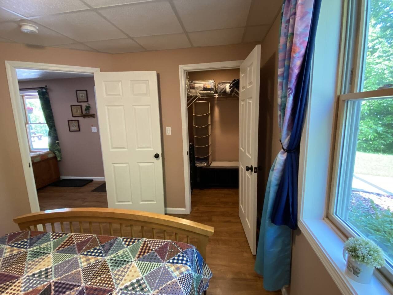 Un dormitorio con cama, armario y ventana con cortinas.