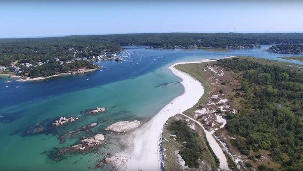 An aerial view of a coastal area with a sandy beach, clear blue waters, rocky outcrops, and dense forested hills. - Clean Waterfront Classic Cottage with Private Beach (Gloucester)