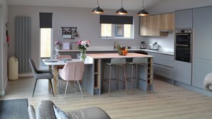 A modern kitchen with a central island, bar stools, and pendant lighting. - 3 bedroom accommodation in Otterburn (Otterburn)