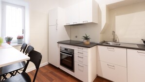 Une cuisine moderne avec des meubles blancs, un four encastré et un plan de travail noir.