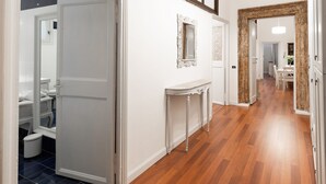 Un couloir doté d’un plancher en bois, de murs blancs et d’une porte blanche donnant sur une salle de bain.