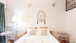 Une chambre à coucher avec un grand lit, une table de chevet, une lampe, un miroir et une bibliothèque.