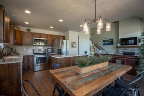 A modern kitchen with wooden cabinets, stainless steel appliances, and a rustic dining table with chairs.